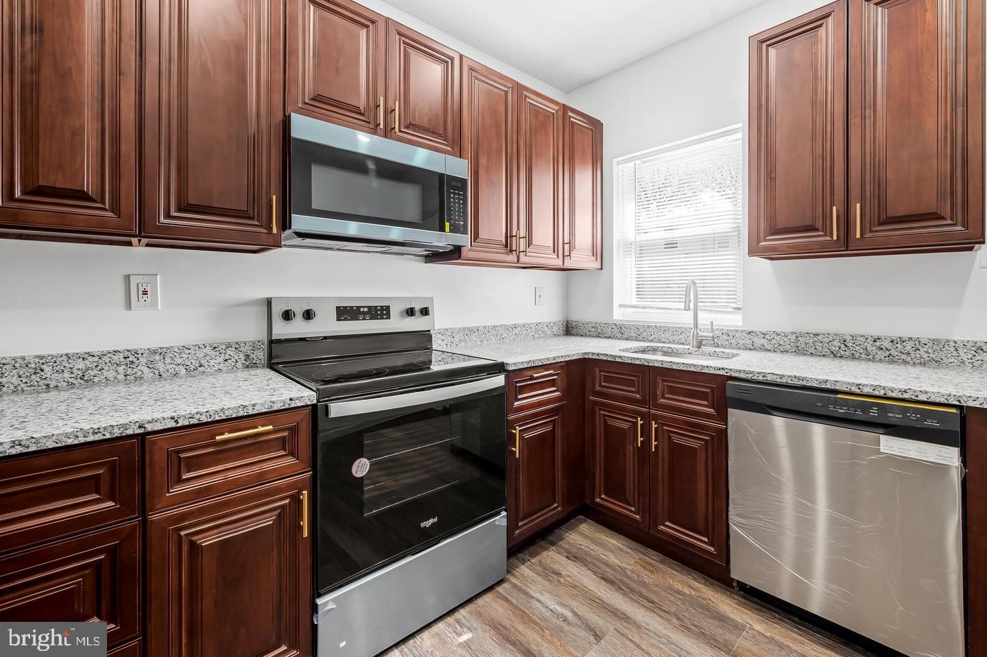 445 Pitman Place Baltimore, MD 21202 - Photo 6 of 29 a kitchen with stainless steel appliances granite countertop wooden cabinets stove top oven and sink
