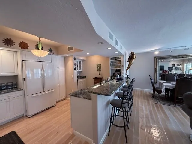 a kitchen with stainless steel appliances a refrigerator a sink dishwasher a dining table and chairs with wooden floor