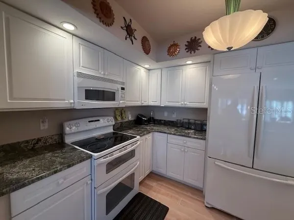 a kitchen with stainless steel appliances granite countertop a sink a stove a refrigerator and cabinets