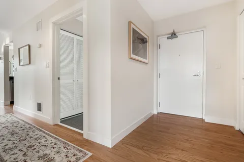 a view of a hallway with wooden floor and cabinet