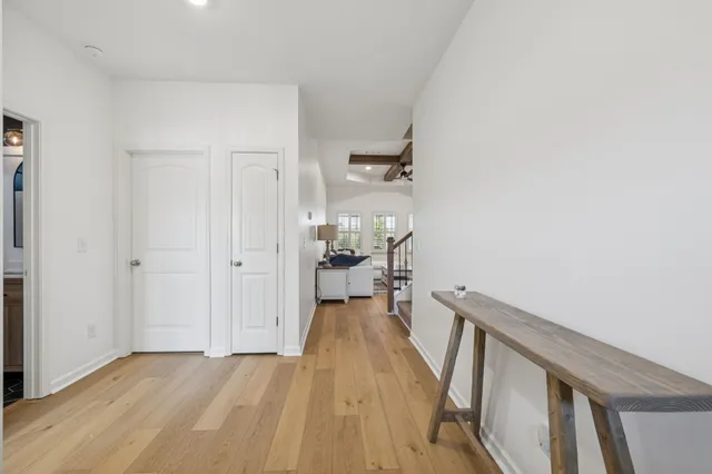 a view of a hallway with wooden floor and a bathroom