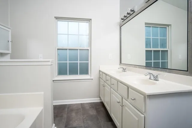 a bathroom with a double vanity sink a mirror and a bathtub