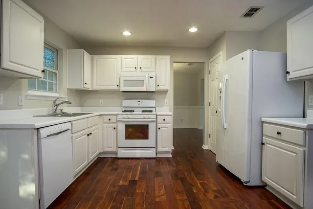 a kitchen with white cabinets and white appliances