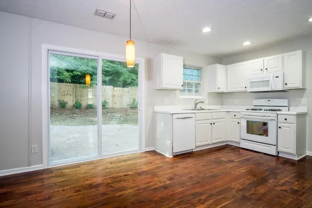a kitchen with stainless steel appliances white cabinets and wooden floors
