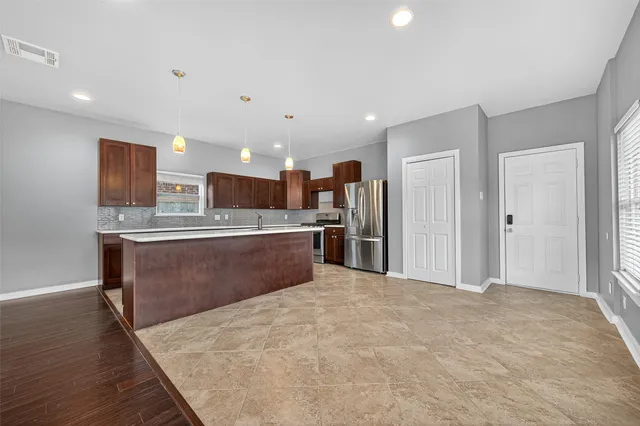 a large kitchen with stainless steel appliances kitchen island a large counter top and a refrigerator