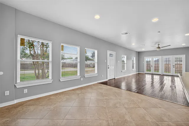 a view of an empty room with a window and wooden floor