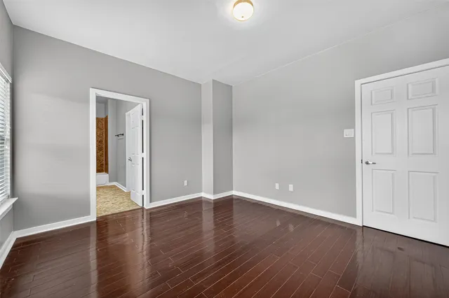 an empty room with wooden floor & closet and windows