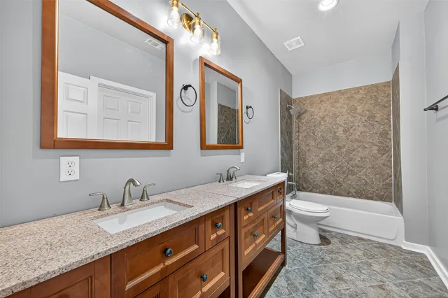 a bathroom with a granite countertop sink mirror vanity bathtub and a toilet