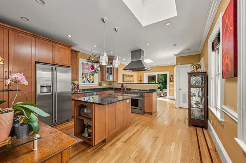 a kitchen with stainless steel appliances granite countertop a refrigerator a stove and a wooden floors