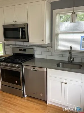a kitchen with granite countertop a sink cabinets and stainless steel appliances