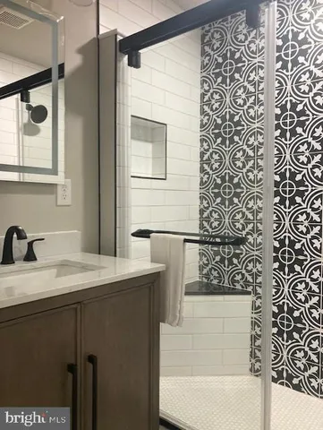 a bathroom with a granite countertop sink a mirror and shower