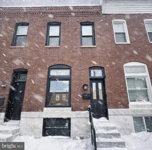 a front view of a brick house with a bench