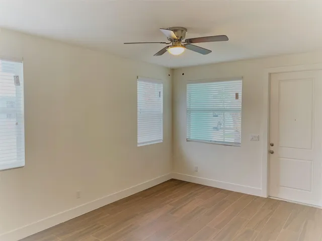 a view of an empty room with wooden floor and a window