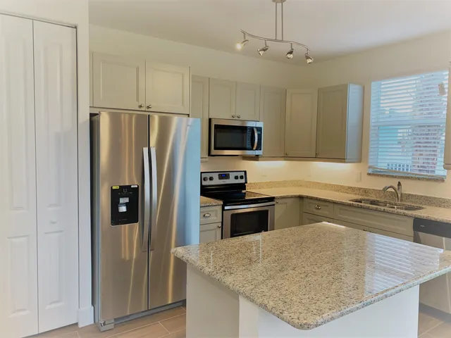 a kitchen with granite countertop a refrigerator and a sink
