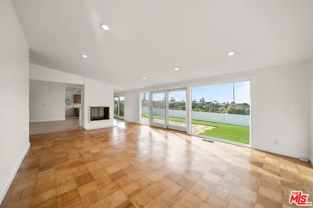 a view of an empty room with a stove and kitchen view