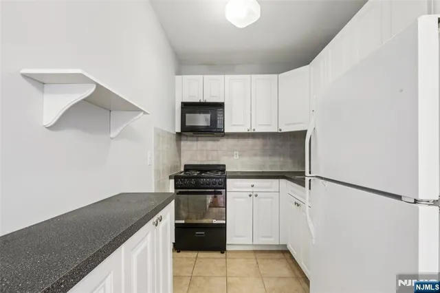 a kitchen with granite countertop white cabinets and black stove top oven with granite countertops
