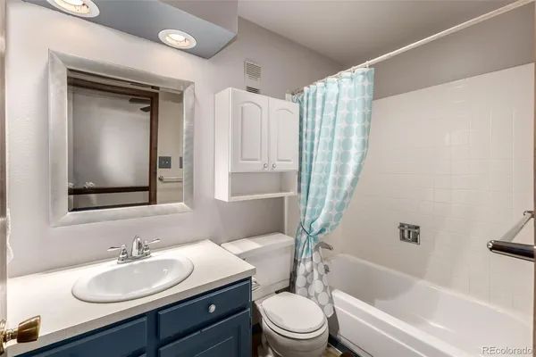a bathroom with a bathtub shower sink vanity mirror and toilet