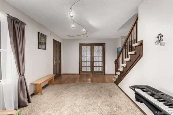 a view of an empty room with wooden floor and stairs