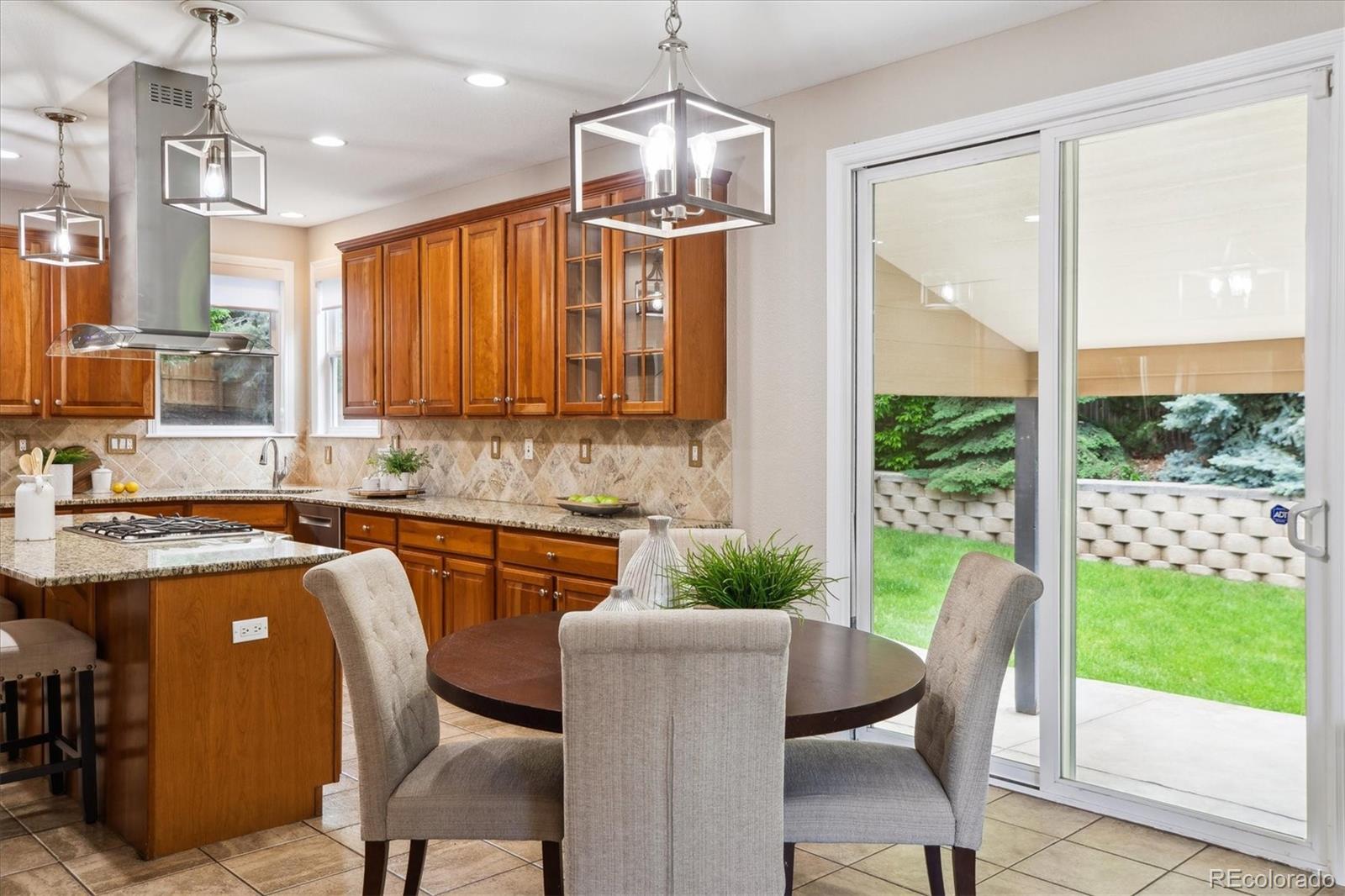 2601 Pemberly Avenue Highlands Ranch, CO 80126 - Photo 14 of 38 a kitchen with kitchen island granite countertop a table chairs and a chandelier