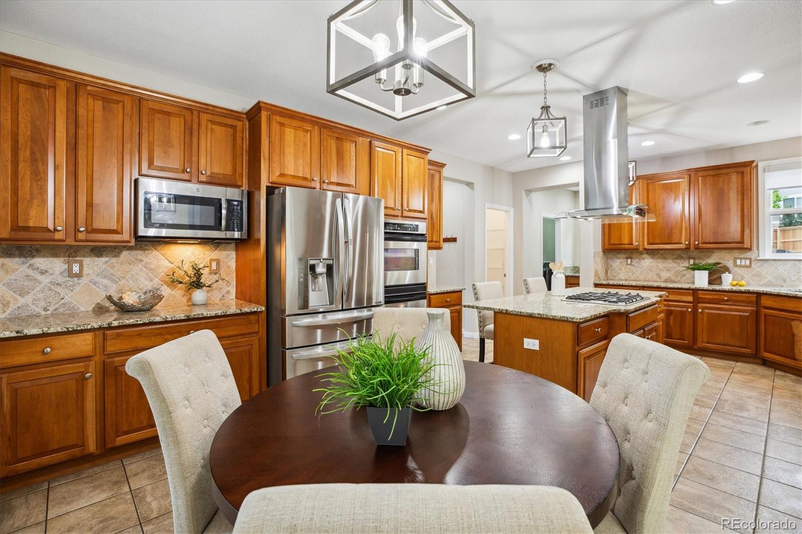 2601 Pemberly Avenue Highlands Ranch, CO 80126 - Photo 15 of 38 a kitchen with stainless steel appliances granite countertop a refrigerator a stove a sink a dining table and chairs with wooden floor