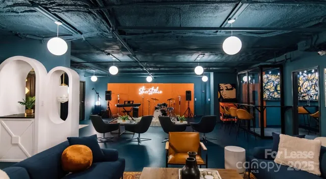 a living room with couches and projector with kitchen view