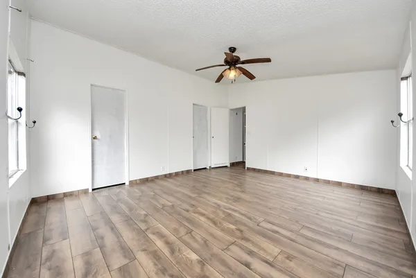 an empty room with wooden floor and windows