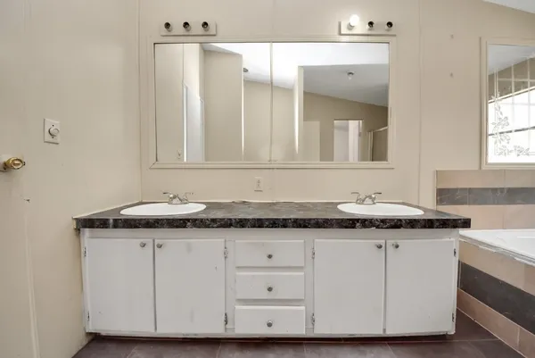 a bathroom with a granite countertop sink and a bathtub