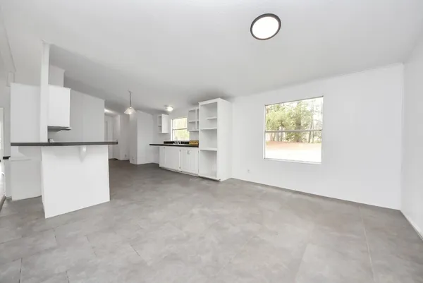 a large white kitchen with stainless steel appliances granite countertop a stove a sink dishwasher and white cabinets with wooden floor