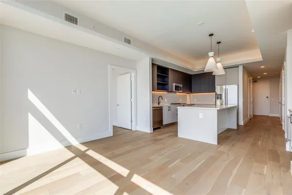 a view of kitchen with stainless steel appliances kitchen island a sink dishwasher a refrigerator and a stove with wooden floor