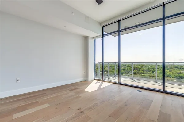 a view of an empty room with wooden floor and glass door