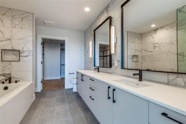 a bathroom with a double vanity sink a mirror and a bathtub