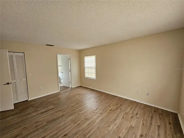 a view of an empty room with wooden floor and window