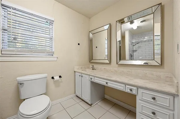 a bathroom with a granite countertop toilet a sink and a mirror