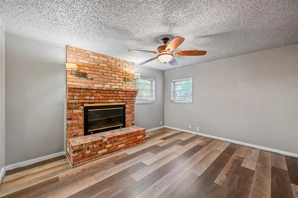 a view of an empty room with window and chandelier fan