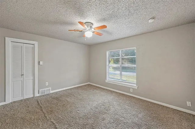 an empty room with windows and fan