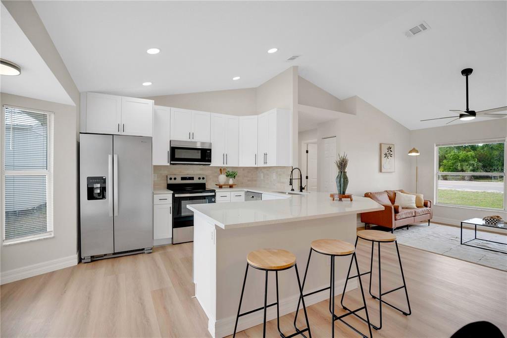 1842 Umbrella Tree Drive Edgewater, FL 32141 - Photo 13 of 32 a kitchen with stainless steel appliances a stove a sink a microwave a refrigerator and cabinets
