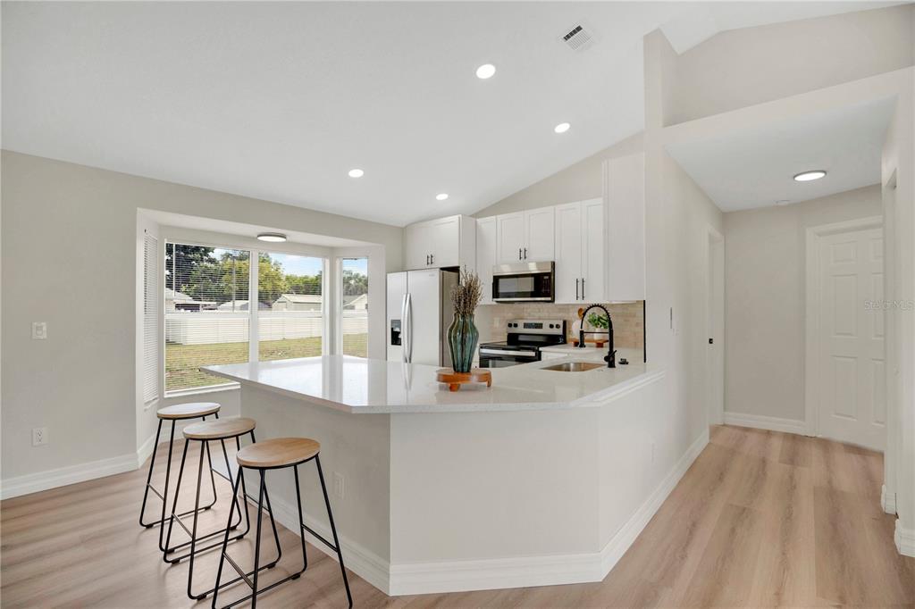 1842 Umbrella Tree Drive Edgewater, FL 32141 - Photo 10 of 32 a kitchen with stainless steel appliances a dining table chairs refrigerator and microwave