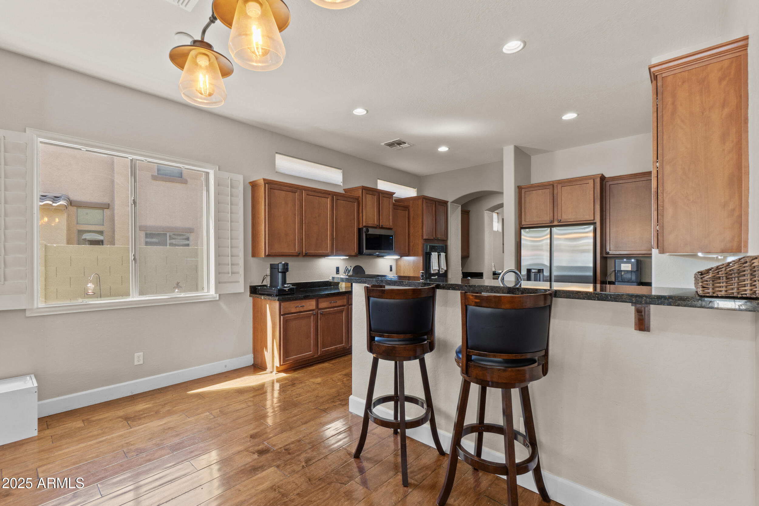 2879 East Janelle Way Gilbert, AZ 85298 - Photo 5 of 33 a kitchen with stainless steel appliances granite countertop a kitchen island a stove a sink a dining table and chairs with wooden floor