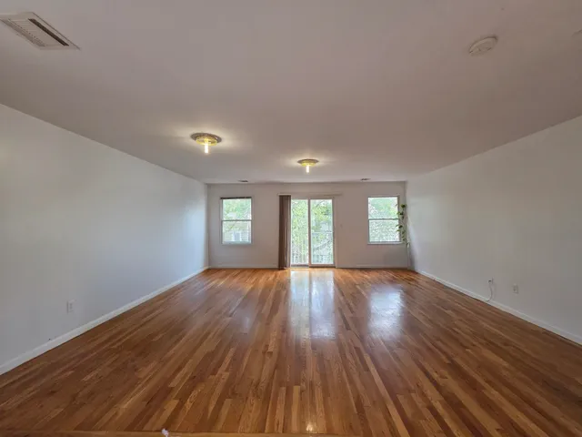 a view of an empty room with wooden floor and window