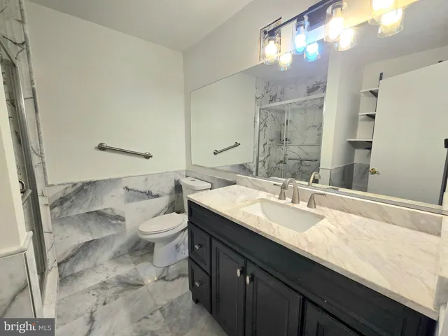 a bathroom with a granite countertop double vanity sink mirror and toilet
