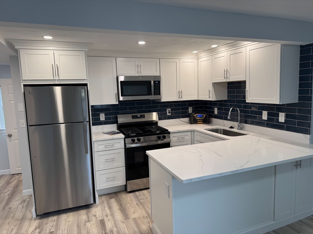 50 Main Street, Unit 3 Woburn, MA 01801 - Photo 2 of 8 a kitchen with a refrigerator a stove a sink and a oven