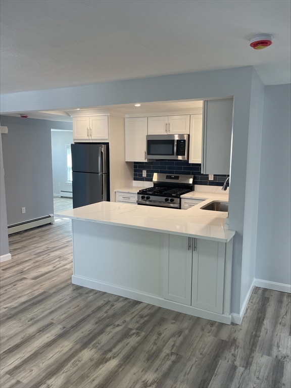 50 Main Street, Unit 3 Woburn, MA 01801 - Photo 3 of 8 a kitchen with stainless steel appliances a stove a sink and a refrigerator