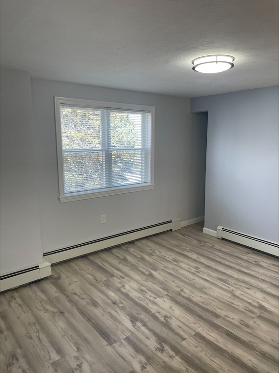 50 Main Street, Unit 3 Woburn, MA 01801 - Photo 4 of 8 a view of an empty room with wooden floor and a window