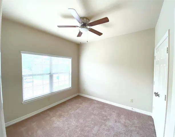 an empty room with a window and a fan
