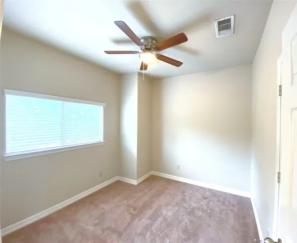 an empty room with windows and fan