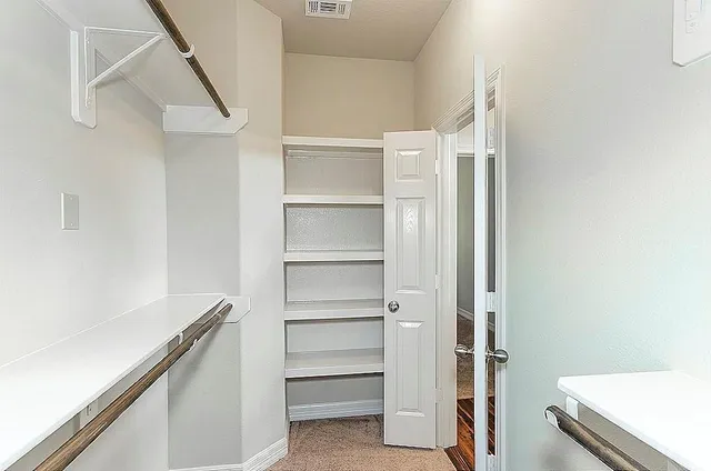 a view of walk in closet with empty racks