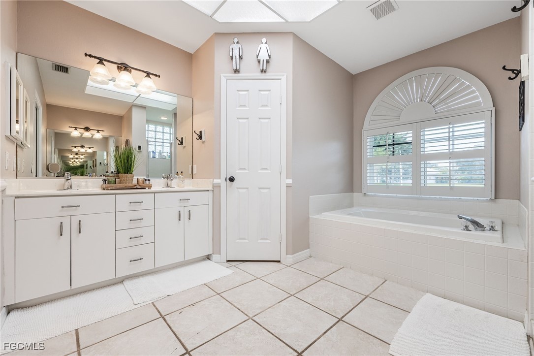 914 Sawgrass Street Clewiston, FL 33440 - Photo 20 of 43 a spacious bathroom with a double vanity sink a mirror a bathtub and next to a window