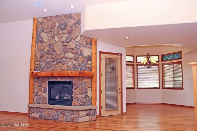 a view of an empty room with wooden floor fireplace and a window