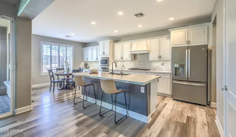 a kitchen with stainless steel appliances granite countertop a refrigerator a sink dishwasher a stove and white countertops with wooden floor