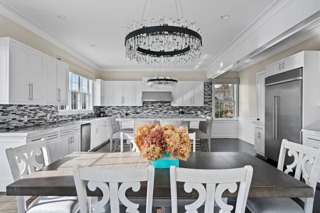a kitchen with stainless steel appliances kitchen island granite countertop a dining table chairs and white cabinets